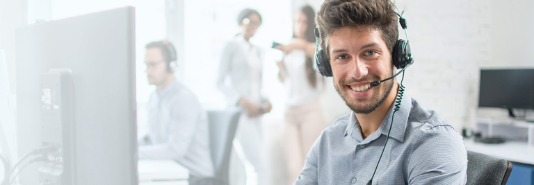 Kontaktanfrage microsonic Foto mit einem Mann mit einem freundlichen Lächeln und direktem Blick. Er trägt ein Headset.